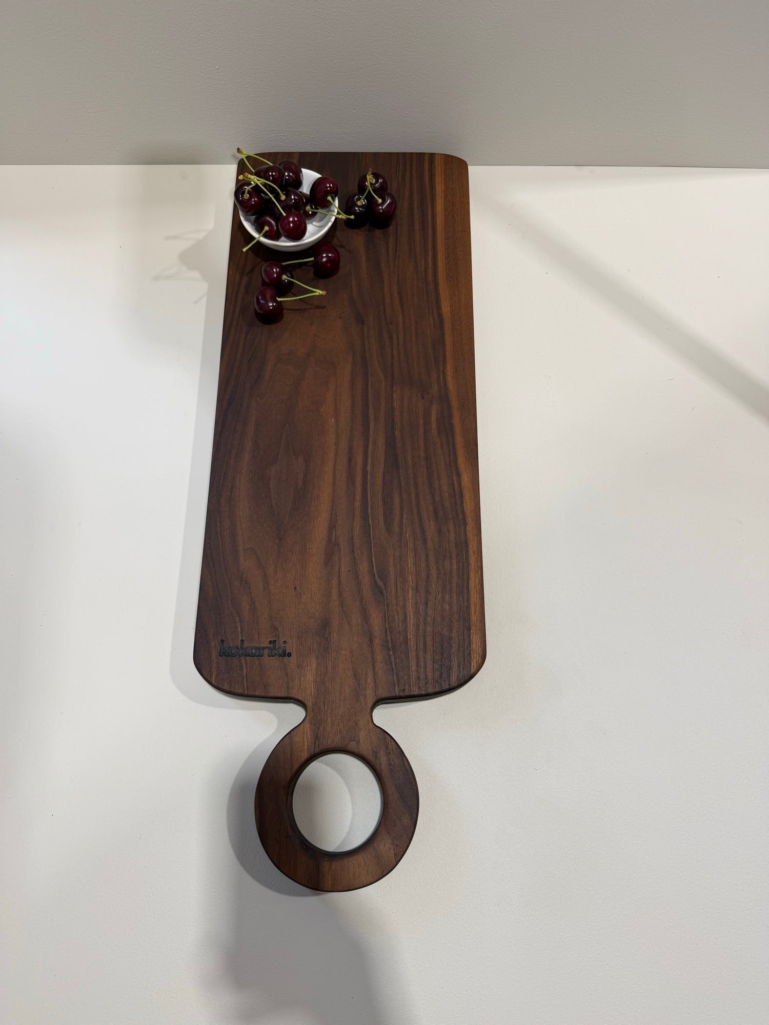 The Halo Serving Board in black walnut — long plank with ring handle